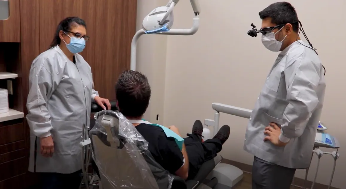 dentist and dental hygienist discuss care plan with patient seated in dental chair